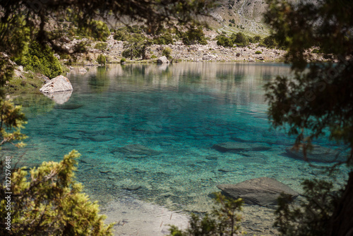view of a blue mountain lake with clear water in which the bottom is visible