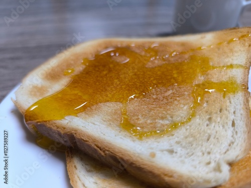 Fried white bread doused with honey on a white plate. photo