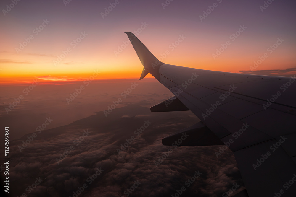 View from the airplane window - lit up sky during sunset time. View from the airplane window - lit up sky during sunset time.