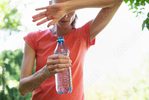 Bild auf Leinwand young woman drinking water in the heat of the day, cooling off from summer heat