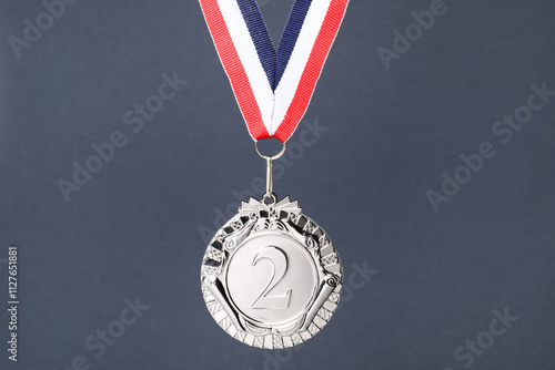 Silver medal with striped ribbon on grey background