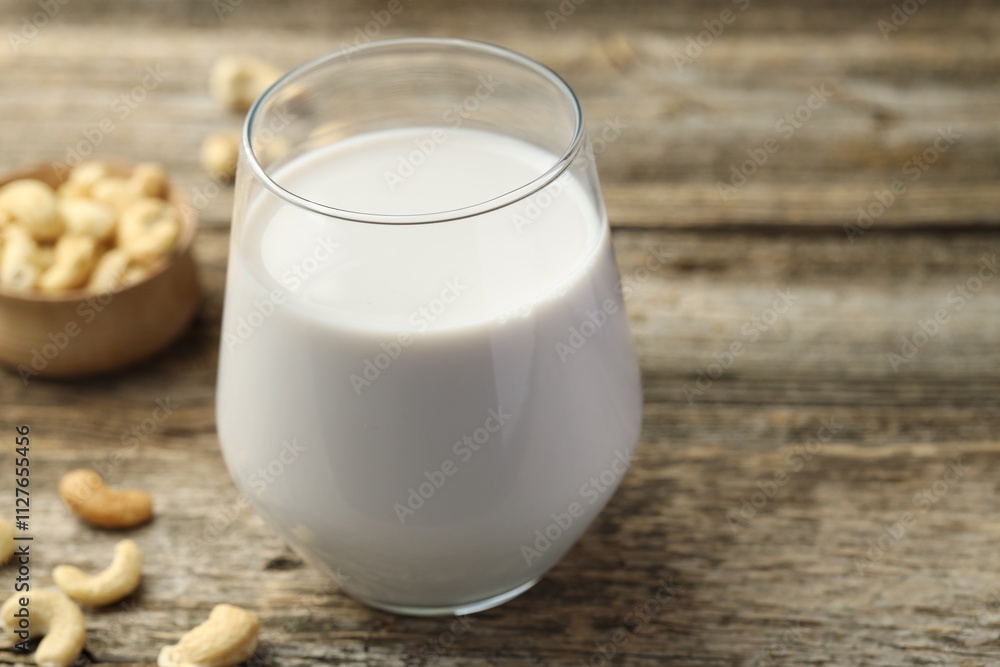 Fresh cashew milk in glass and nuts on wooden table, closeup Fresh cashew milk in glass and nuts on wooden table, closeup
