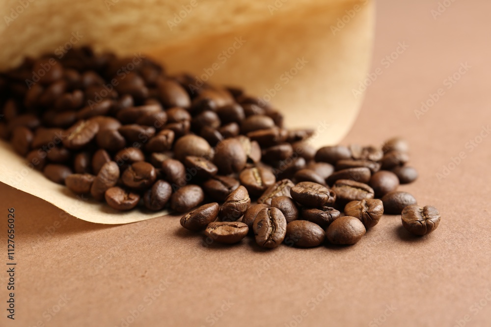 Fototapeta premium Paper coffee filter and beans on brown background, closeup