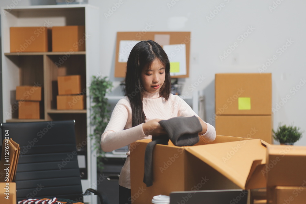 Startup SME small business entrepreneur of freelance Asian woman wearing apron using laptop and box to receive and review orders online to prepare to pack sell to customers, online sme business ideas. Startup SME small business entrepreneur of freelance Asian woman wearing apron using laptop and box to receive and review orders online to prepare to pack sell to customers, online sme business ideas.