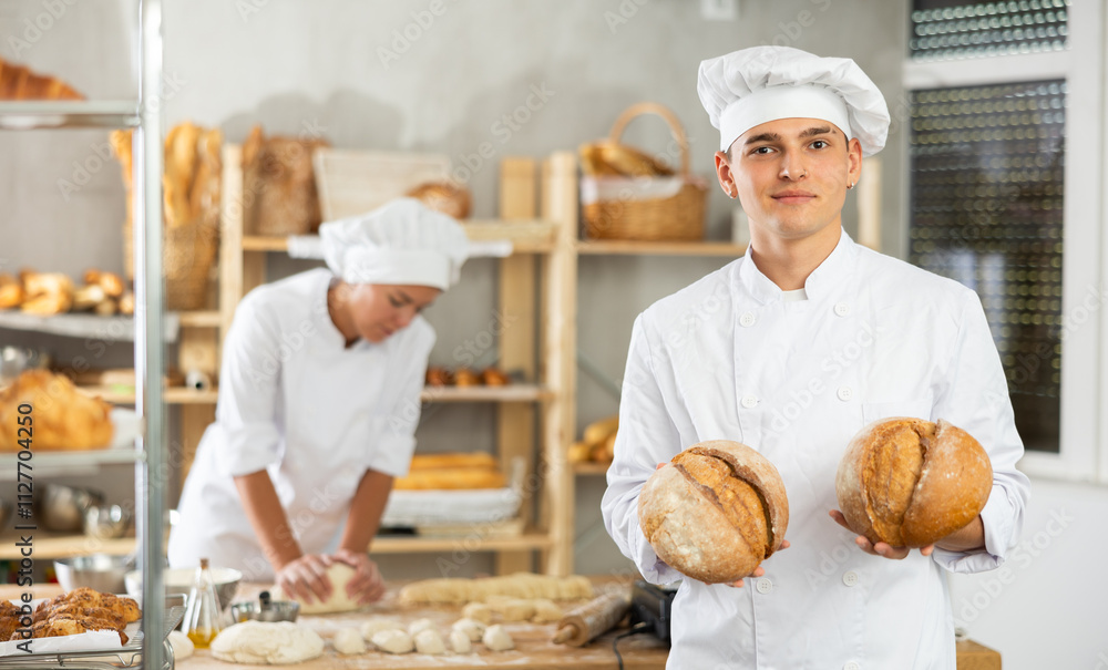 Bakery male employee holds ready-made bread of bread in hands Bakery male employee holds ready-made bread of bread in hands