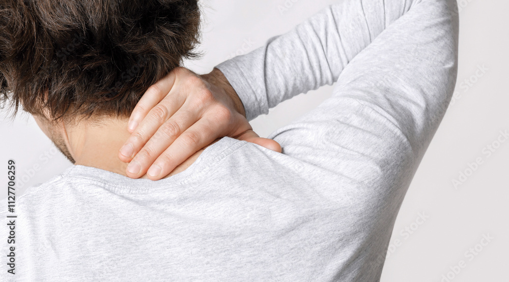 Pain in neck from work. Guy presses his hand to sore spot, back, close up, studio shot Pain in neck from work. Guy presses his hand to sore spot, back, close up, studio shot