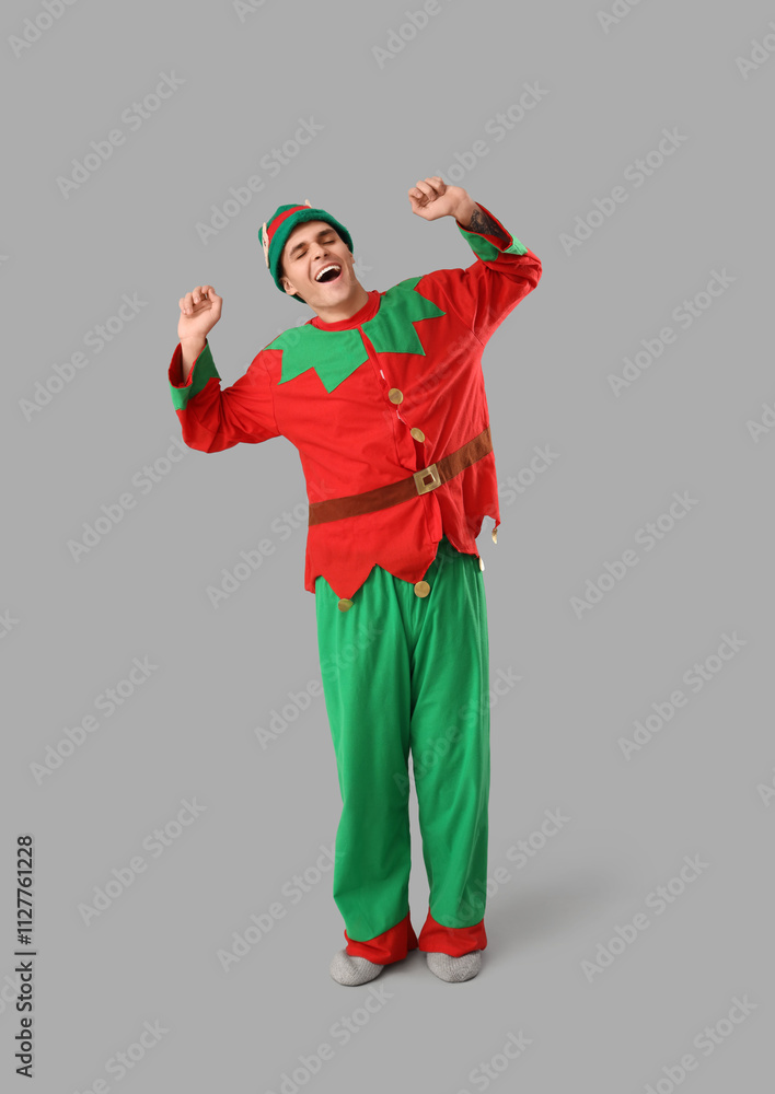 Handsome young man in elf's costume on grey background Handsome young man in elf's costume on grey background