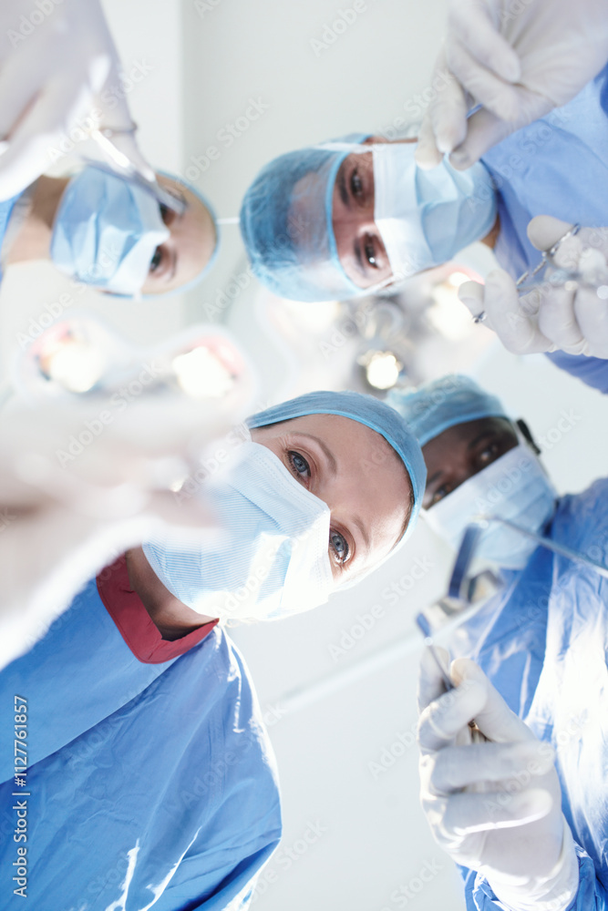 © peopleimages.com - Low angle, people or surgeons in hospital for surgery, emergency accident or healthcare in theatre. Mask, tools or doctors in surgical scrubs in operating room for teamwork, cutting safety or help
