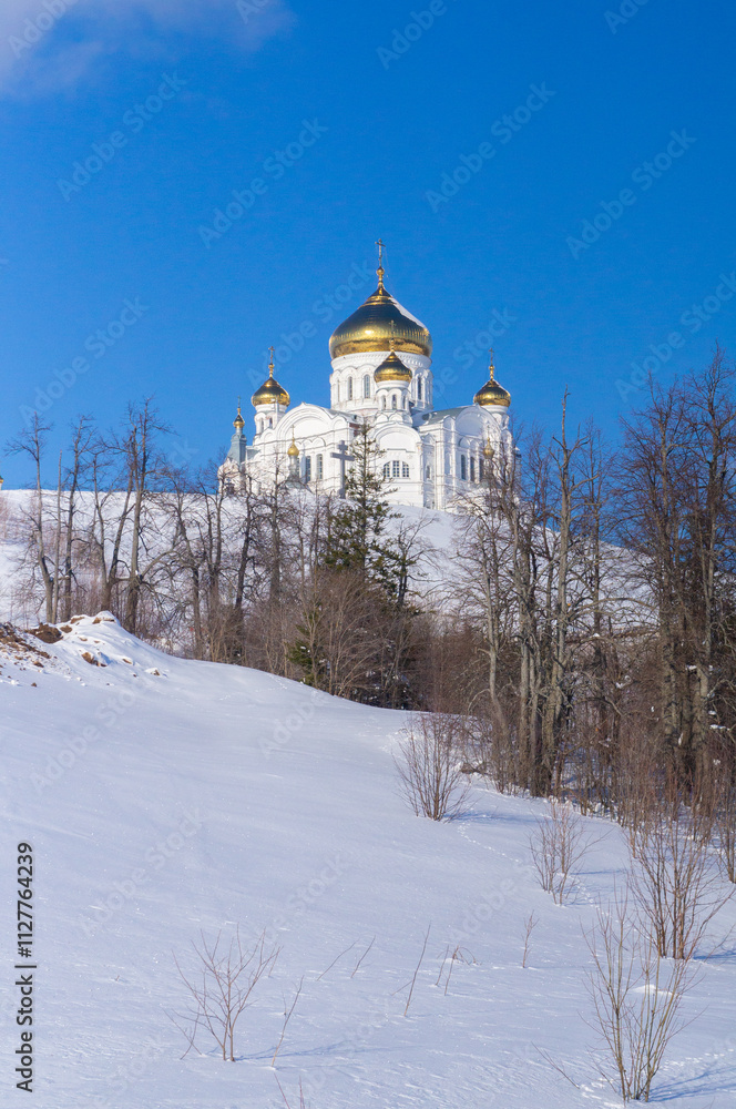 A majestic Orthodox church with golden domes stands out against the blue sky in winter. A majestic Orthodox church with golden domes stands out against the blue sky in winter.