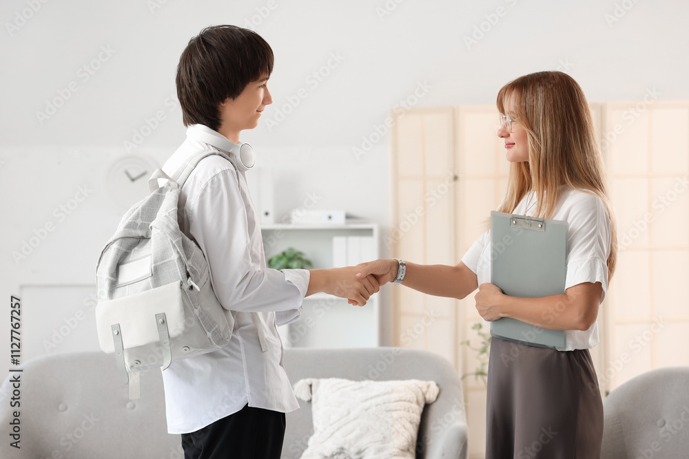 Female psychologist with teenage boy shaking hands in office Female psychologist with teenage boy shaking hands in office