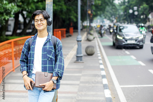 Young Student Man Enjoying Music With Headphones on Urban Sidewalk