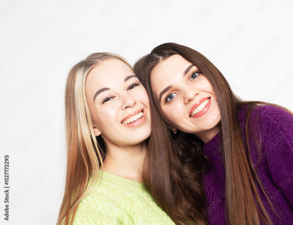 Two cheerful girlfriends laughing and hugging on a white background. Two cheerful girlfriends laughing and hugging on a white background.
