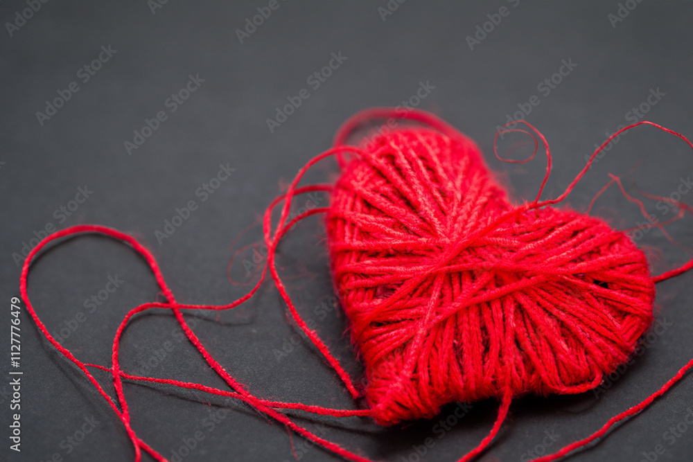 Is surrounded by red yarn. Heart shaped background with gray heart thread. Red heart lying on a red background with a gray thread. A red heart lying on lifestyle a gray background. Is surrounded by red yarn. Heart shaped background with gray heart thread. Red heart lying on a red background with a gray thread. A red heart lying on lifestyle a gray background.
