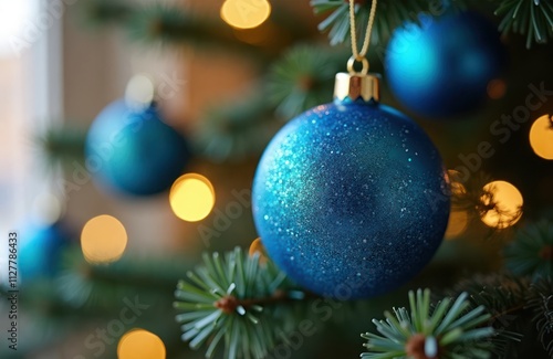 Blue Christmas ornament on tree branch. Warm lights illuminate scene. Holiday decorations. Winter holidays ambiance. Festive atmosphere. Christmas tree. Festive glow. Ornaments. Festive. Festive photo