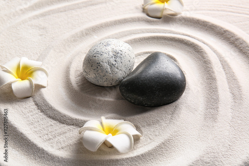 Photography Stones and tropical flowers on light sand with lines in Japanese rock garden