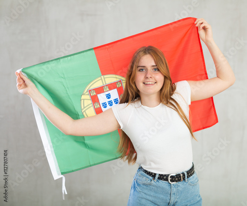 Attractive smiling female football fan holding Portugal flag