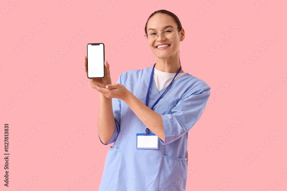 Female doctor with blank mobile phone on pink background Female doctor with blank mobile phone on pink background