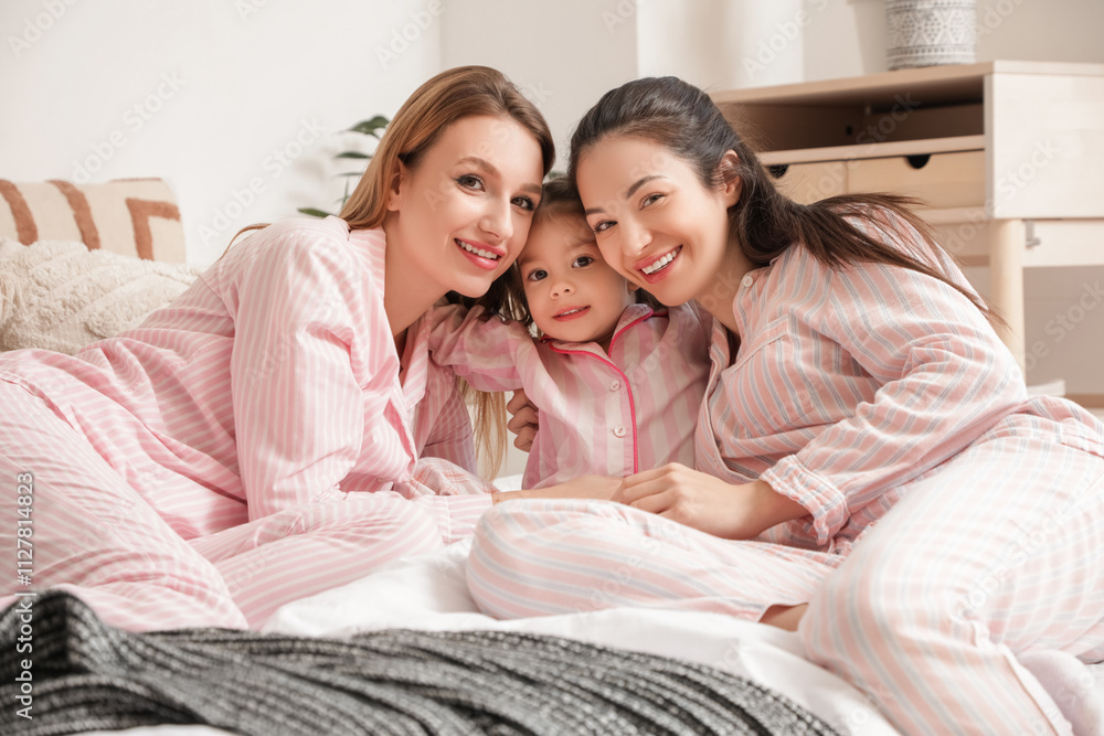 Young lesbian couple with their little daughter hugging in bedroom Young lesbian couple with their little daughter hugging in bedroom