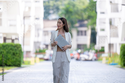 A woman is walking down a street holding a laptop bag