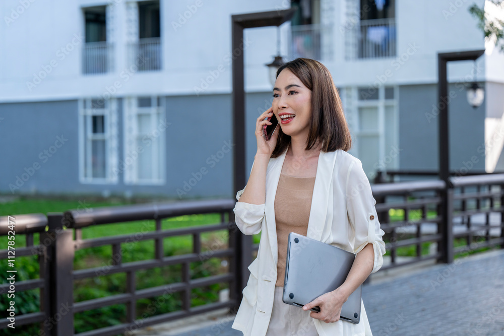 A woman is talking on her cell phone while walking down a sidewalk A woman is talking on her cell phone while walking down a sidewalk