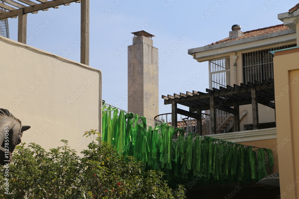 A tall building with a chimney and a green ribbon hanging from it A tall building with a chimney and a green ribbon hanging from it