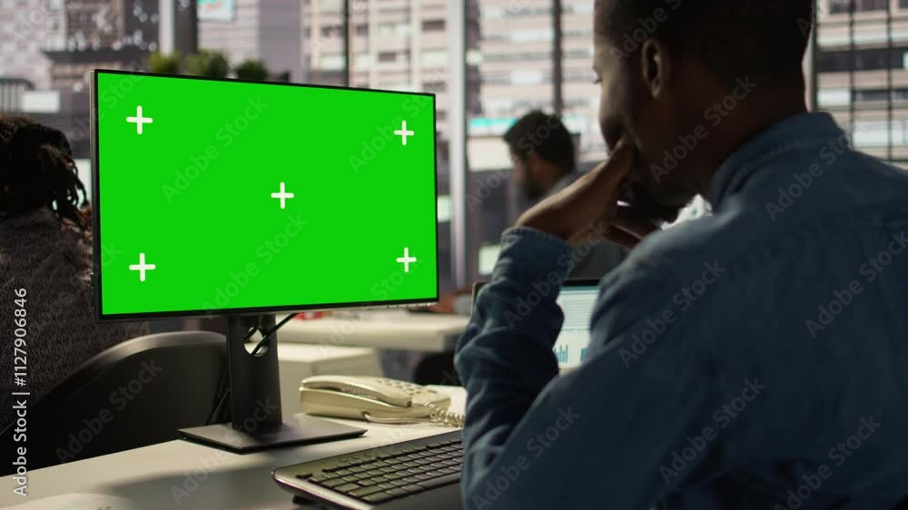 Male administrator focused on financial planning next to chroma key screen, reviewing infographics for data analysis and company strategy. Businessman ensuring enterprise solutions. Camera B. Male administrator focused on financial planning next to chroma key screen, reviewing infographics for data analysis and company strategy. Businessman ensuring enterprise solutions. Camera B.