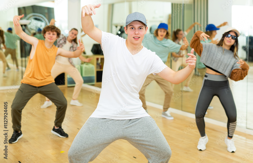 Fototapeta premium Teens training hip-hop dance moves during group rehearsal in studio.