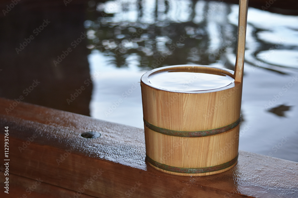 檜の露天風呂に置かれた檜の手桶　水面に反射する景色