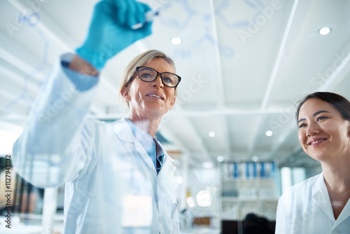 Foto Women, scientist and mentor with formula on glass wall at laboratory for teamwork, collaboration or ideas on research