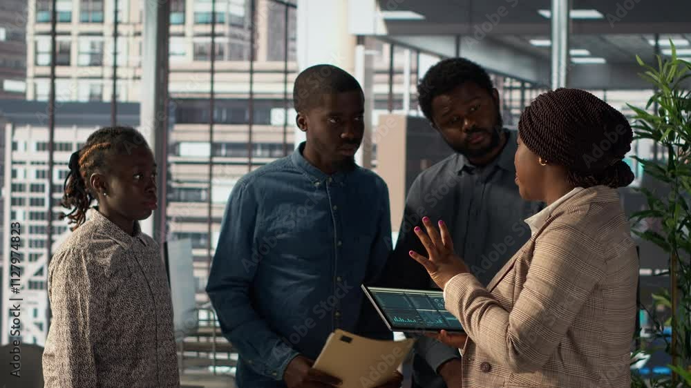African american manager examines company strategy with her staff in a high end office, making key business decisions to support enterprise development. Establish resource allocation. Camera A. African american manager examines company strategy with her staff in a high end office, making key business decisions to support enterprise development. Establish resource allocation. Camera A.