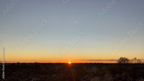 Foto Sunrise in Uluru / Ayers Rock in a land of Buffel grass which is also known as bush grass and dry grass that grows in the land of red sand in Uluru
