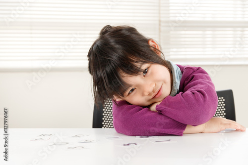 数字のカードを机の上にならべて、余裕の笑顔を見せる小学生の女の子 photo