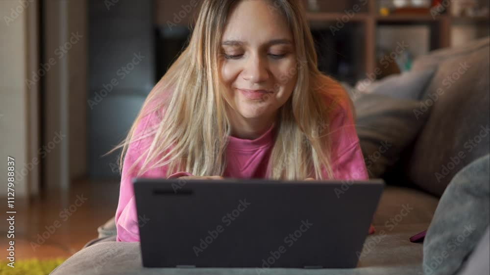 Watching videos on a notebook pc, reading an e-book at home, using laptop pc. young woman using laptop pc online application for work on dark background. freelancer works at home lying on the couch. Watching videos on a notebook pc, reading an e-book at home, using laptop pc. young woman using laptop pc online application for work on dark background. freelancer works at home lying on the couch.