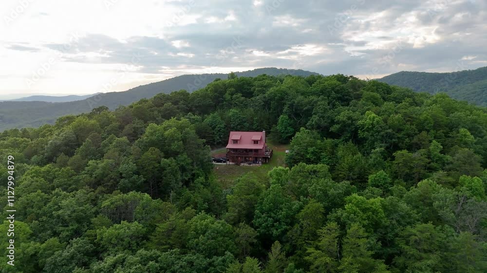 Drone shot pulling out from a cabin in the woods in Ellijay, Georgia at sunset.
