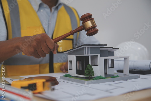 Judge gavel on building blueprint plans with a yellow safety helmet in the background. law that deals with matters relating to building construction, engineering. Construction law concept. photo