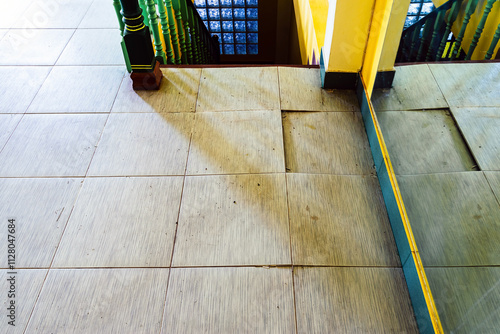 Background with falling off tiled tiles in living room. Close up of cracked ceramic tiles on a residential house floor surface due to improper construction material. Old tile floor cracked and broken.