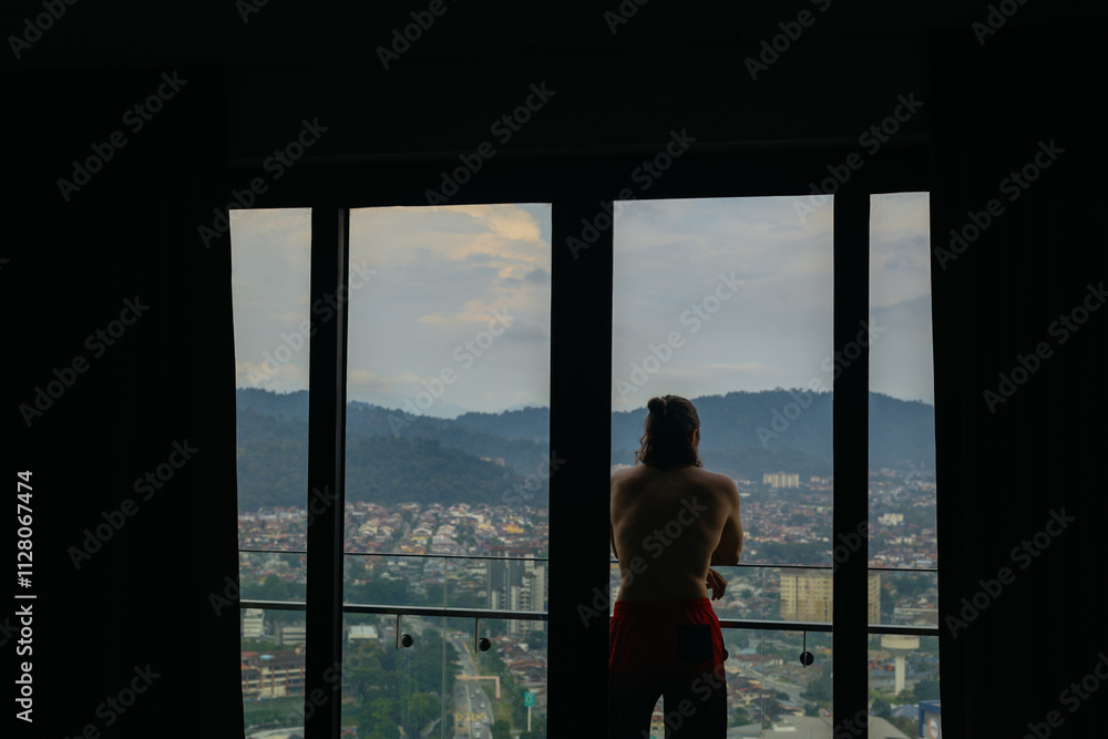 Male adult enjoying cityscape view from balcony at sunset Male adult enjoying cityscape view from balcony at sunset