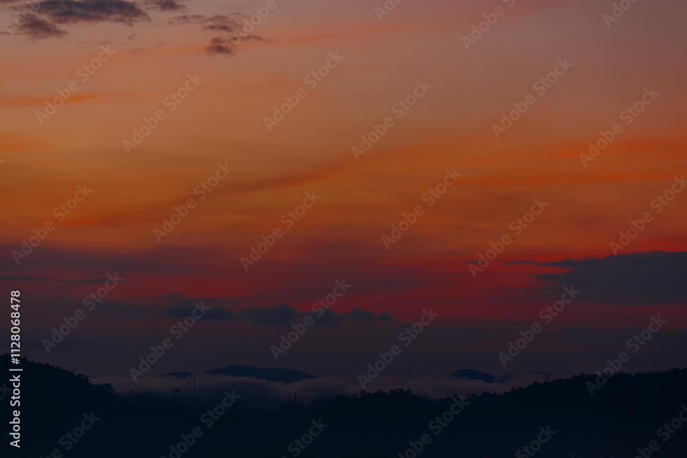 Vibrant orange and red sunset over misty hills Vibrant orange and red sunset over misty hills