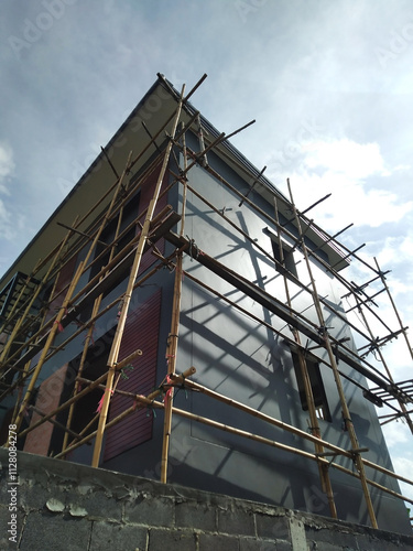 Bamboo scaffolding surrounding modern building under construction