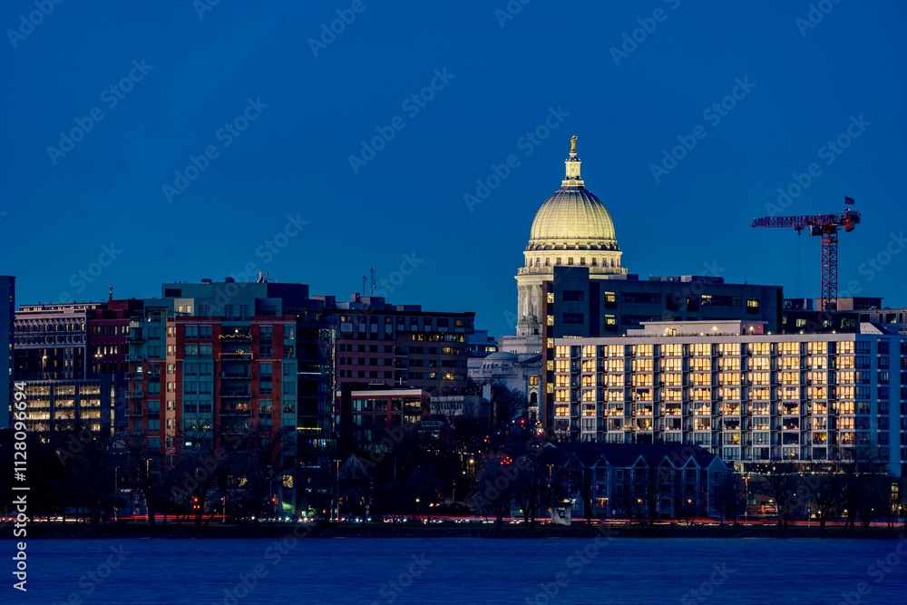 Obraz premium Downtown Madison, WI and the Wisconsin State Capitol Building behind Lake Monona at Twilight