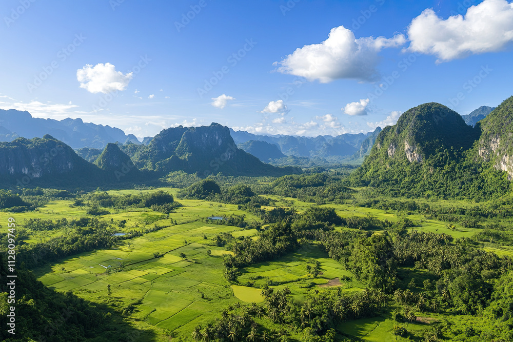 Obraz premium Aerial view of a lush green valley surrounded by towering mountains under a clear blue sky