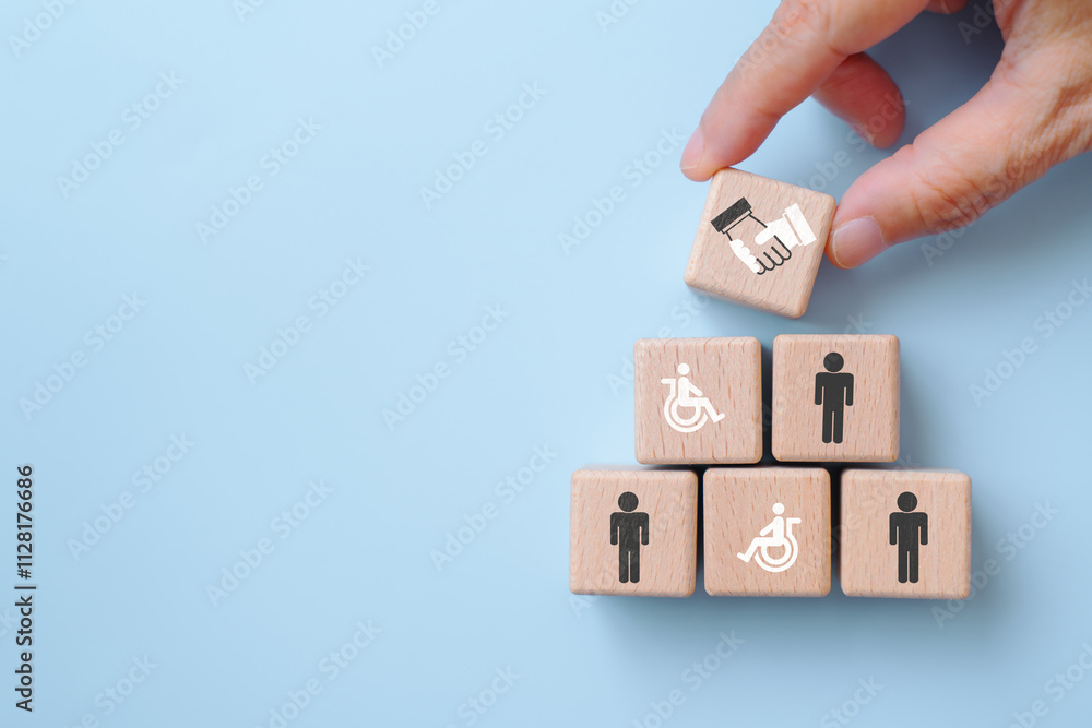 For supported employment and inclusive workplace concept. wooden cube blocks with disabled person and men icons, hand place handshake sign on top on blue background For supported employment and inclusive workplace concept. wooden cube blocks with disabled person and men icons, hand place handshake sign on top on blue background