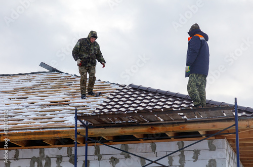 Wallpaper Mural Two men are working on a roof, one of them wearing a blue jacket Torontodigital.ca