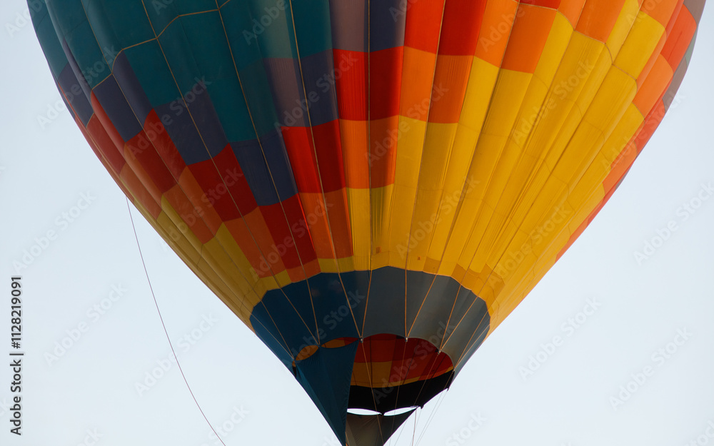 Fototapeta premium A hot air balloon with a colorful pattern is floating in the sky