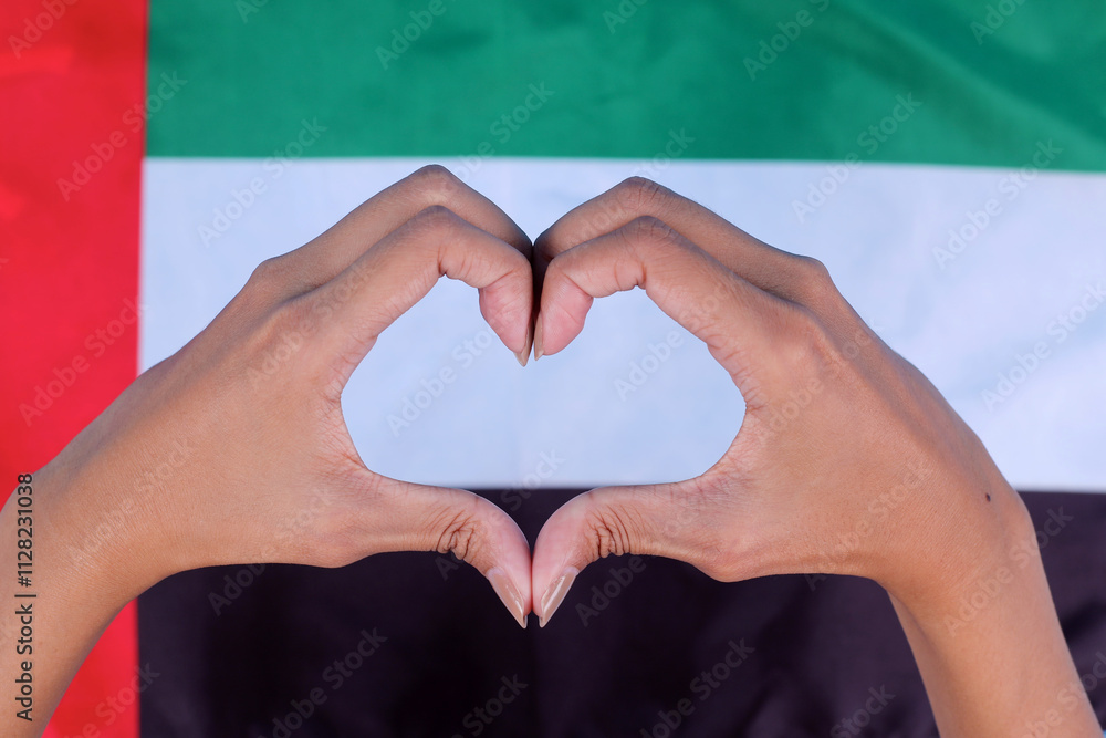 Fototapeta premium Close Up of Hands Showing Heart Sign With UAE National Flag Background