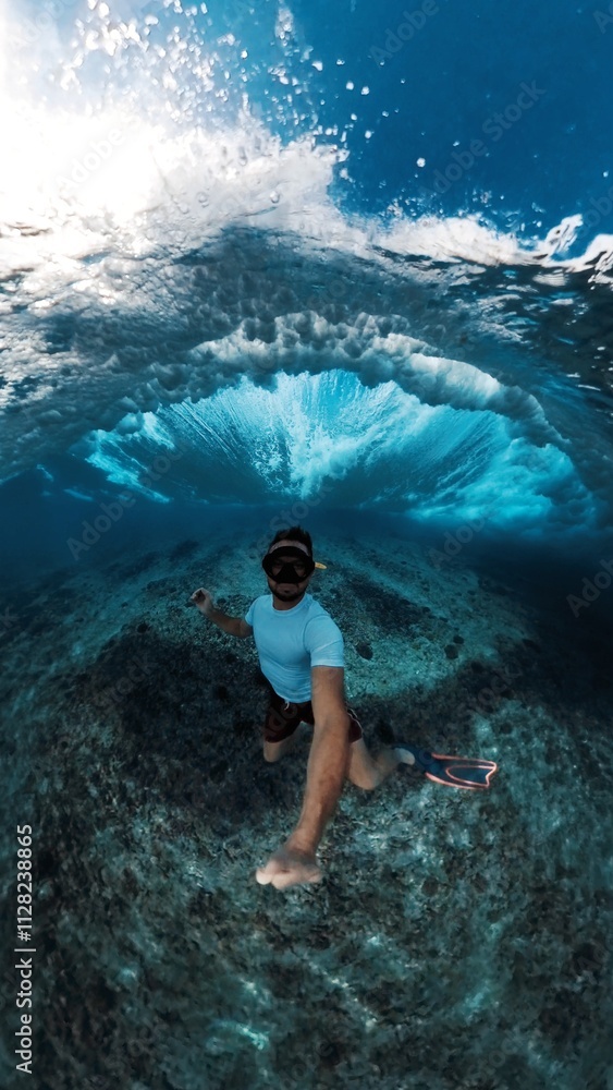Fototapeta premium Man with mask dives under the breaking ocean wave