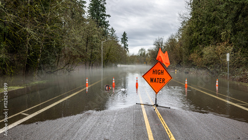 Signs and cones at a road barricade. Street of HIllsboro closed due to high water after a rainfall