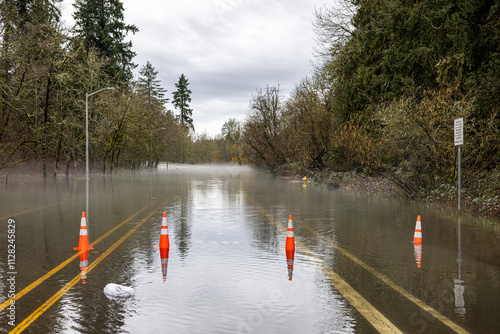 Signs and cones at a road barricade. Street of HIllsboro closed due to high water after a rainfall