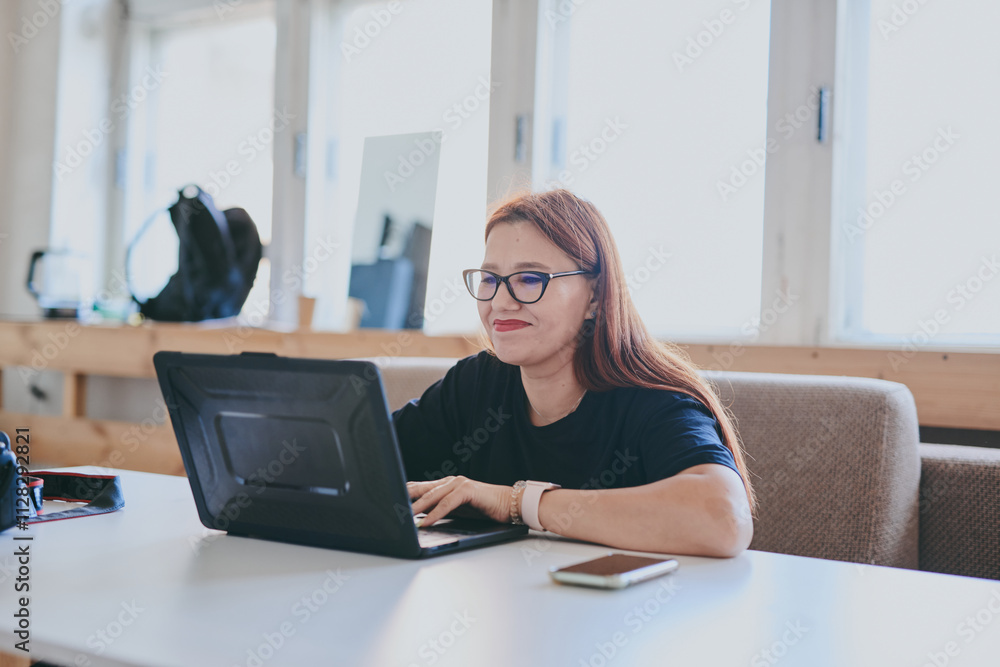 Female photographer with laptop on table processing shots in professional photo studio Female photographer with laptop on table processing shots in professional photo studio