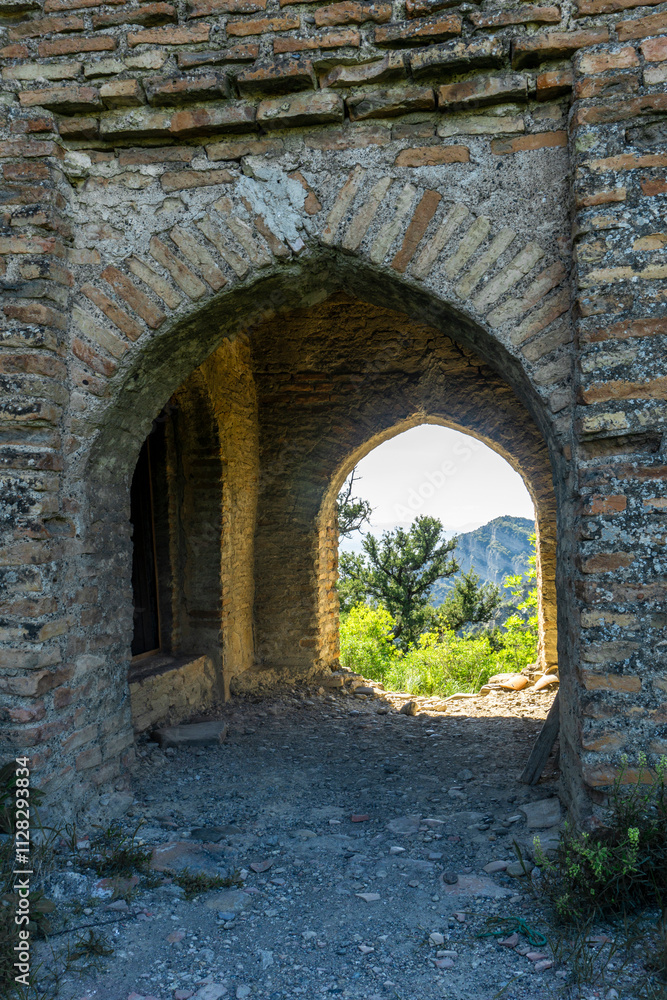 View of the mountain and tree through the arch. The church on the hill among bushes and trees is part of the Shio-Mgvime monastery. View of the mountain and tree through the arch. The church on the hill among bushes and trees is part of the Shio-Mgvime monastery.
